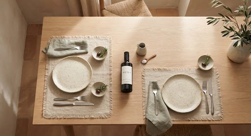 A laid table — ceramic plates, linen and olive oil in afternoon light